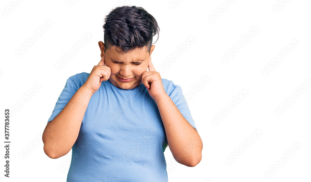 Little boy kid wearing sports workout clothes covering ears with fingers with annoyed expression for the noise of loud music. deaf concept. Little boy kid wearing sports workout clothes covering ears with fingers with annoyed expression for the noise of loud music. deaf concept.
