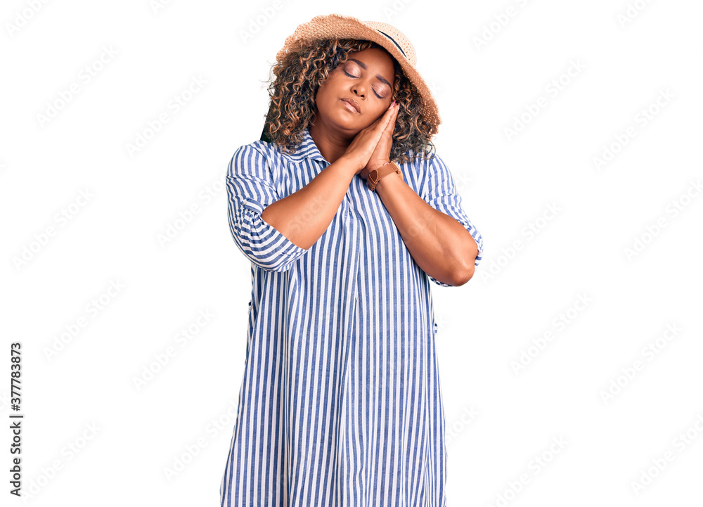 Young african american plus size woman wearing summer hat sleeping tired dreaming and posing with hands together while smiling with closed eyes. Young african american plus size woman wearing summer hat sleeping tired dreaming and posing with hands together while smiling with closed eyes.