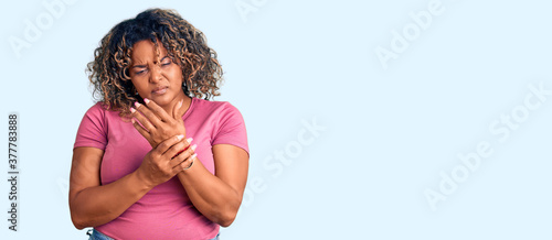 Young african american plus size woman wearing casual clothes suffering pain on hands and fingers, arthritis inflammation photo
