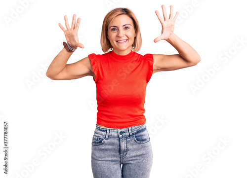 Young blonde woman wearing casual clothes showing and pointing up with fingers number ten while smiling confident and happy.