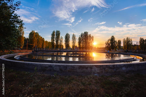 Modern sewage treatment plant. Round wastewater purification tank at sunset