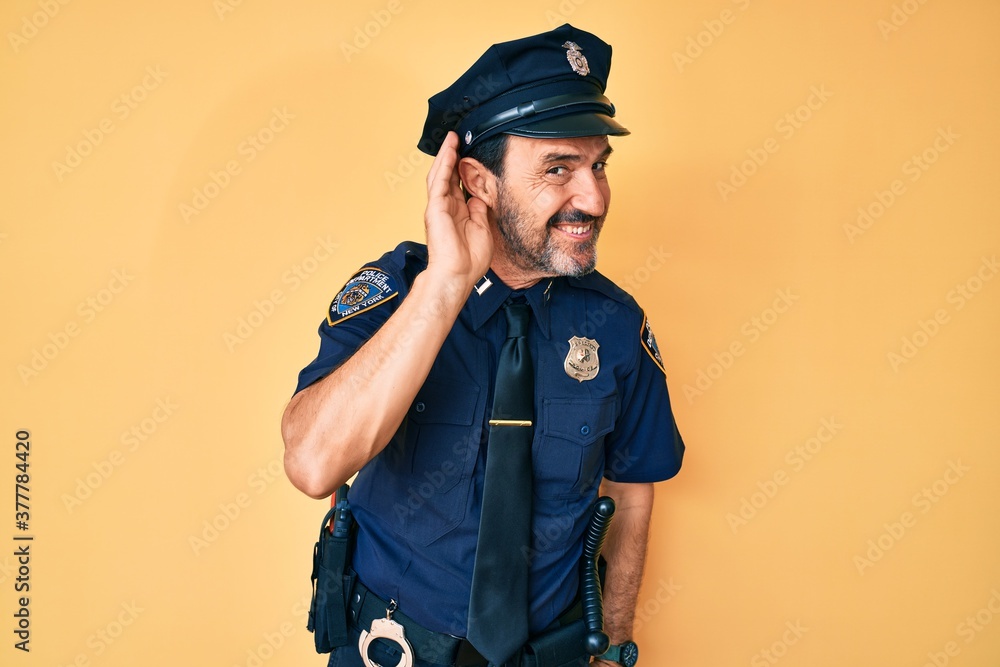 Middle age hispanic man wearing police uniform smiling with hand over ear listening an hearing to rumor or gossip. deafness concept. Middle age hispanic man wearing police uniform smiling with hand over ear listening an hearing to rumor or gossip. deafness concept.
