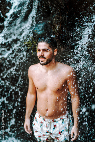 Joven atractivo en cascada mojandose