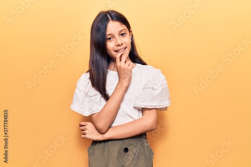 Beautiful child girl wearing casual clothes smiling looking confident at the camera with crossed arms and hand on chin. thinking positive.