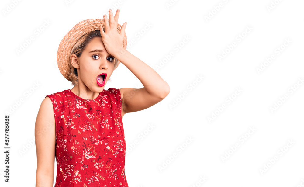 Young beautiful blonde woman wearing summer hat surprised with hand on head for mistake, remember error. forgot, bad memory concept. Young beautiful blonde woman wearing summer hat surprised with hand on head for mistake, remember error. forgot, bad memory concept.