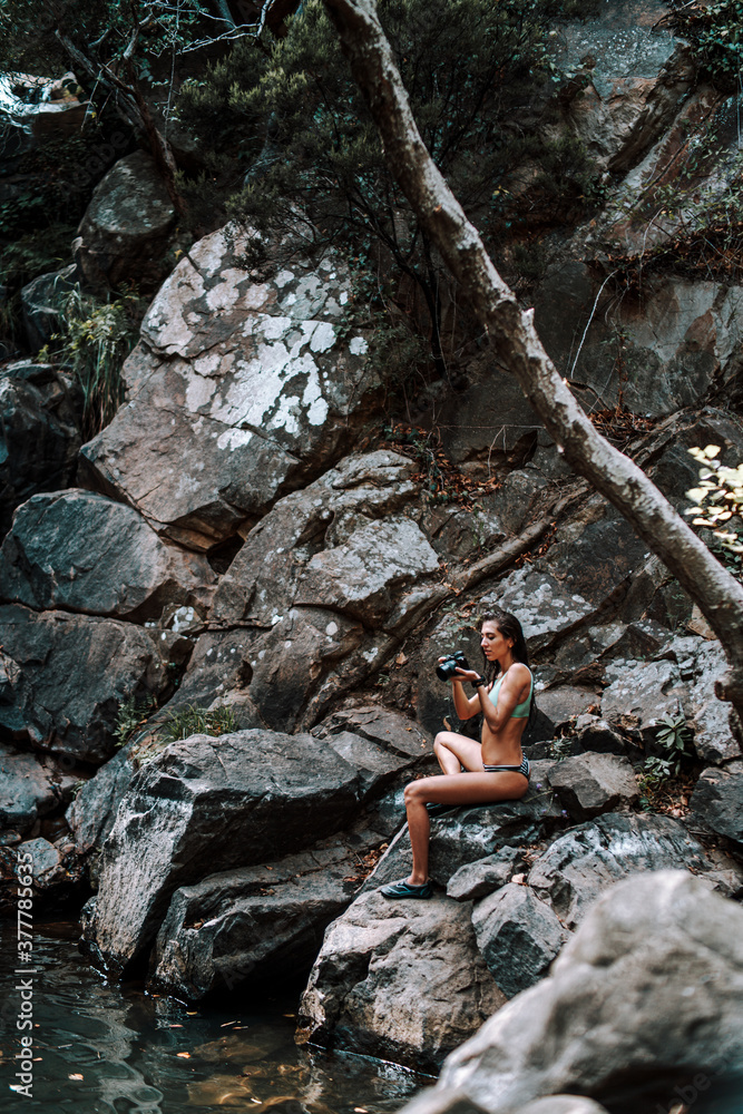 Chica joven atractiva en lago posando sobre una piedra