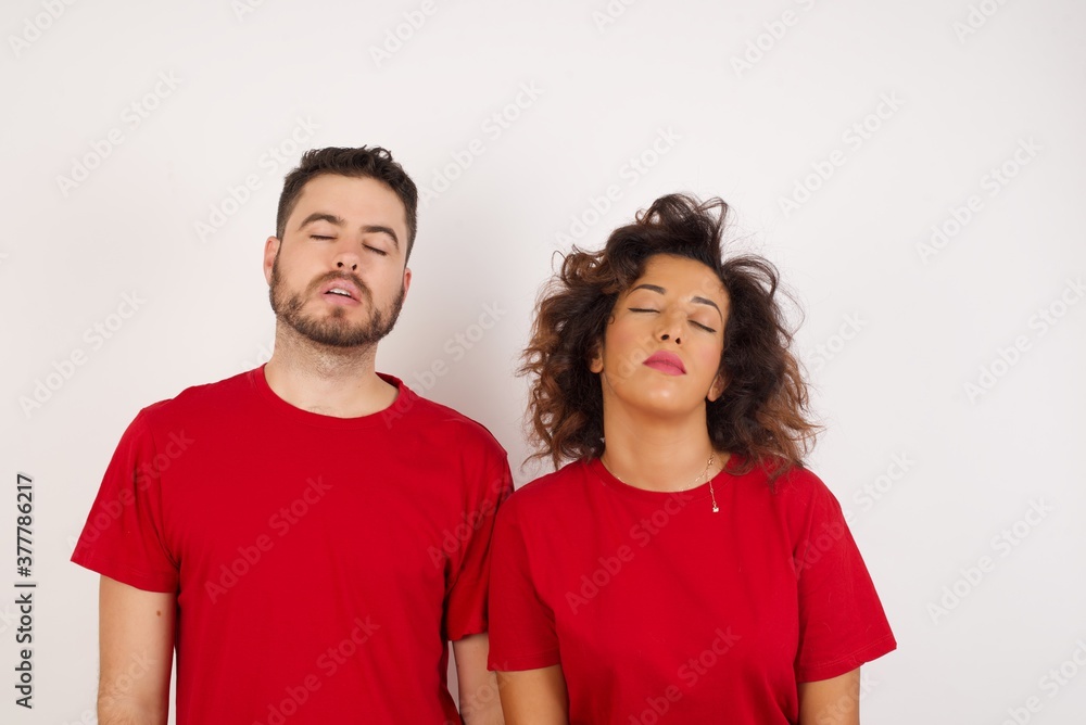 Young beautiful couple wearing red t-shirt on white background looking sleepy and tired, exhausted for fatigue and hangover, lazy eyes in the morning. Young beautiful couple wearing red t-shirt on white background looking sleepy and tired, exhausted for fatigue and hangover, lazy eyes in the morning.