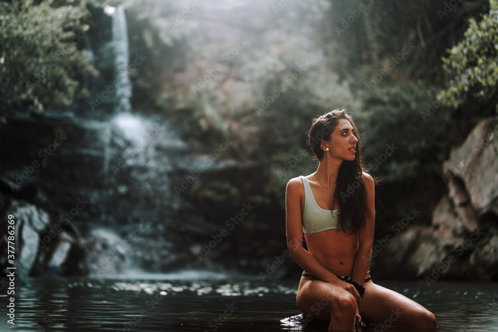 Chica joven atractiva en lago posando sobre una piedra Chica joven atractiva en lago posando sobre una piedra