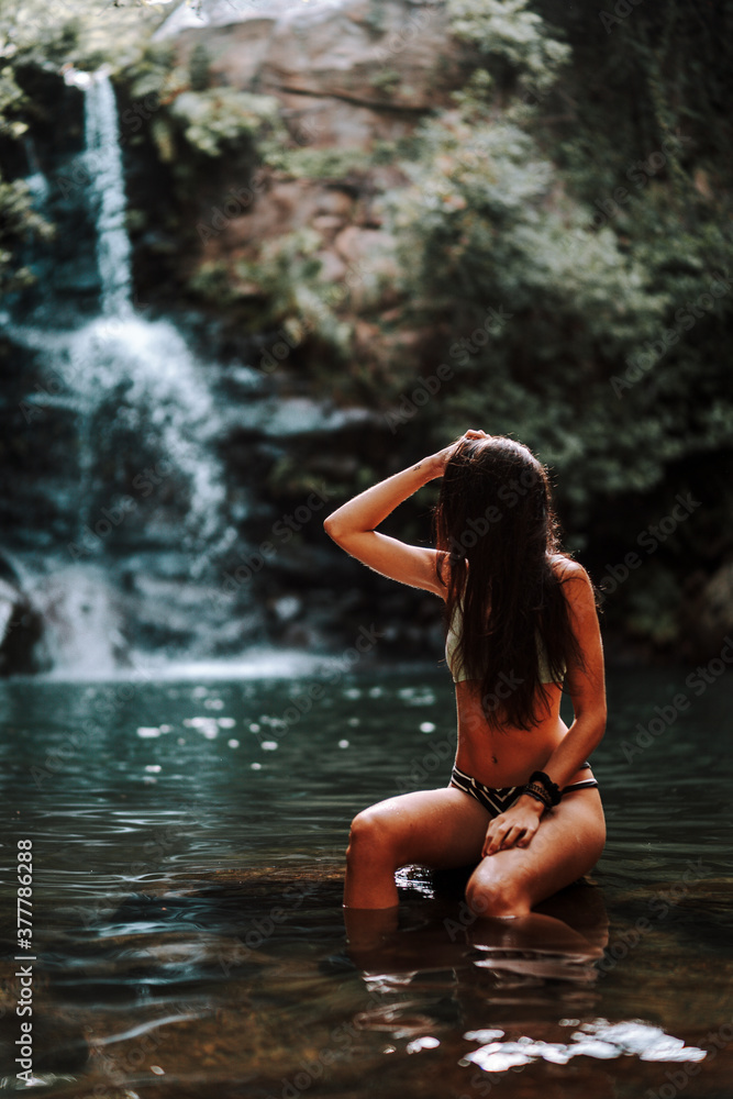Chica joven atractiva en lago posando sobre una piedra Chica joven atractiva en lago posando sobre una piedra