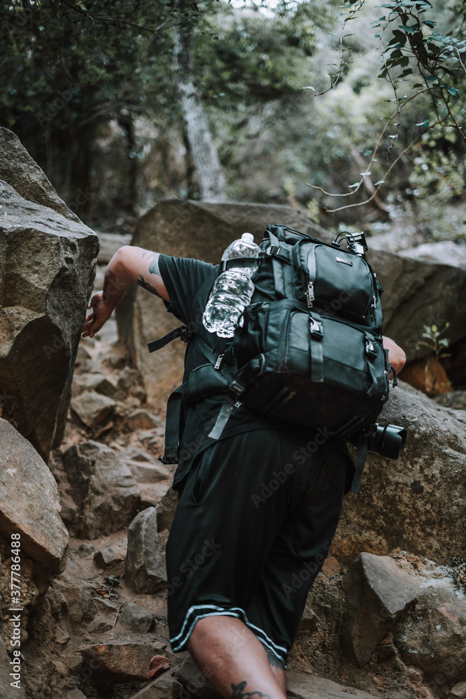 Joven explorador fotografo camina por medio de un valle seco en la naturaleza con su equipo fotografico Joven explorador fotografo camina por medio de un valle seco en la naturaleza con su equipo fotografico