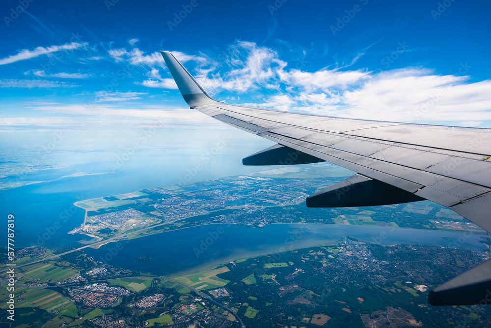 Fototapeta premium Boeing 737 wing. Flight over Amsterdam. blue sky with white clouds