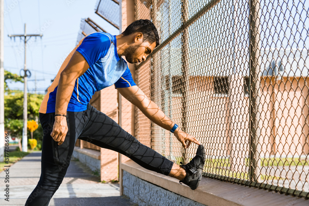 portrait of young athletic hispanic man doing stretching exercises with his left foot. portrait of young athletic hispanic man doing stretching exercises with his left foot.