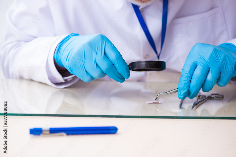 Old male expert criminologist working in the lab for evidence Old male expert criminologist working in the lab for evidence