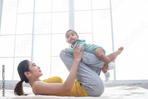 Asian mother fit and play Yoga for lose weight after delivery a new born baby in home, sports mother is engaged in fitness mom, mother, exercise and healthy concept.