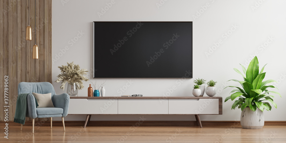 Smart TV on the white wall in living room with armchair,minimal design. Smart TV on the white wall in living room with armchair,minimal design.