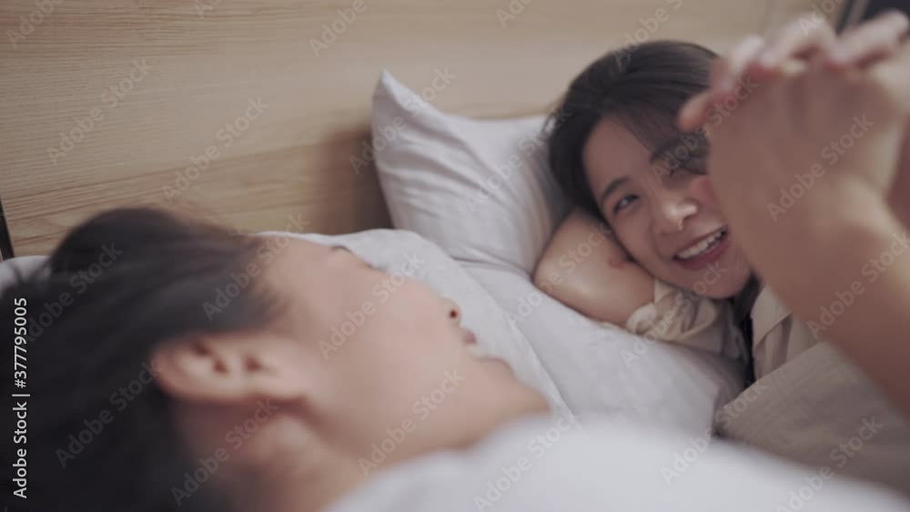 Asian lgbt lesbian couple lying on bed, holding hands playing with each other, LGBT freedom, bonding relationship, comfortable bedroom warm blanket, sexual equality sharing love, transgender movement Asian lgbt lesbian couple lying on bed, holding hands playing with each other, LGBT freedom, bonding relationship, comfortable bedroom warm blanket, sexual equality sharing love, transgender movement