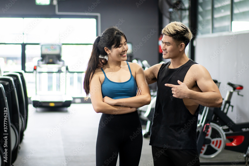 Cheerful healthy Asian sportspeople portrait in a gym with copyspace. Asian young sportswoman and sportsman posing for a photography in a indoor gym. Wellness and wellbeing in healthy people concept.