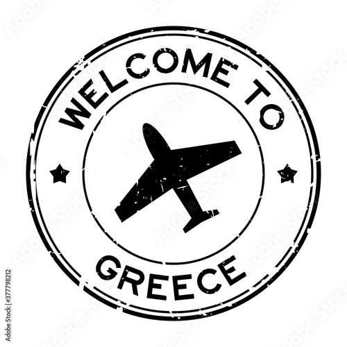Grunge black welcome to Greece word with airplane icon round rubber seal stamp on white background