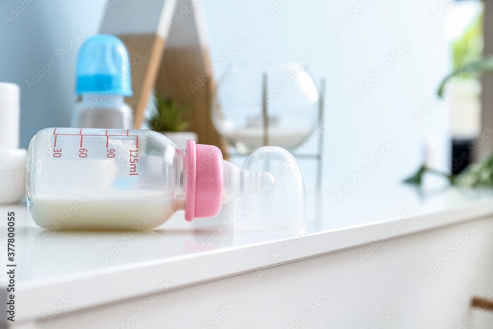 Bottle of milk for baby on table in room Bottle of milk for baby on table in room