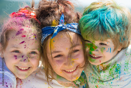 Painted kids face on colorful background holi, closeup. Festival of colors. Children draws paints.