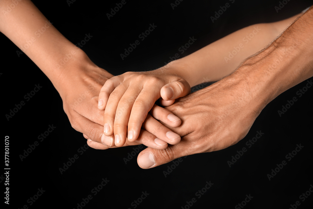 Hands of family on dark background