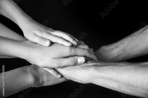 Hands of family on dark background
