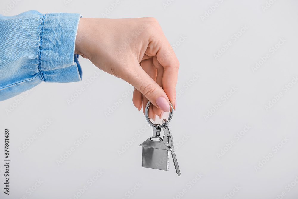 Female hand with key from house on light background Female hand with key from house on light background