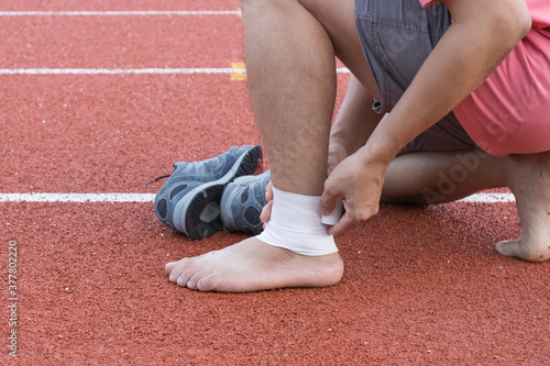 man applying compression bandage onto ankle injury of a football player, Sports injuries, concept First aid for ankle injuries