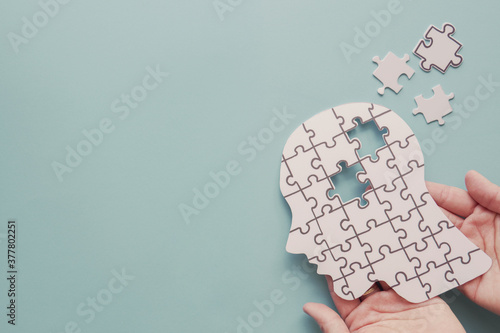 Hands holding brain with puzzle paper cutout, autism, demential, Epilepsy and alzheimer awareness, seizure disorder, world mental health day concept