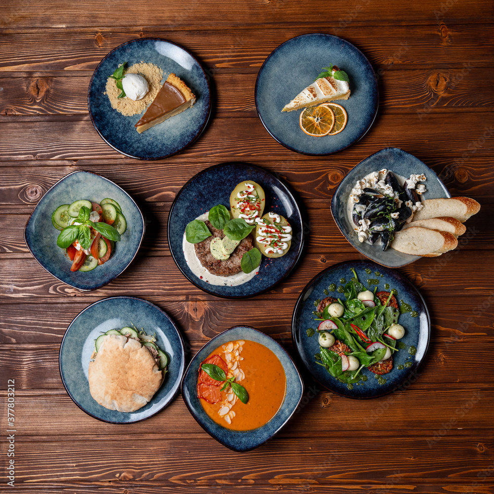 Assortment of european meals, placed in a circle, on a wooden table, above view