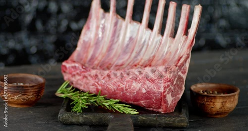 A large piece of raw rack of lamb slowly rotates.  photo