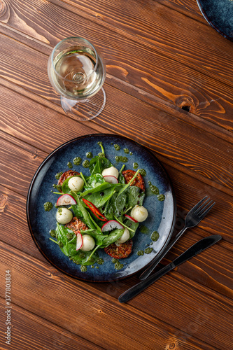 Spinach and mozzarella salad with cherry tomatoes and chili slices, classic salad served with white wine, a posh modern restaurant