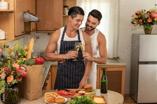 Happy LGBT couples cook in the home family kitchen together with love  smile and romantic moment with a champagne toast