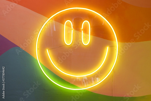 Happy Face in neon light blub with a colorful background.