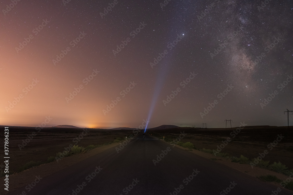 Milky Way on night sky and standing man silhouette on road with flashlight . Colorful night landscape. Exploring the universe