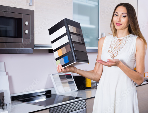 Beautiful salesgirl of furnishing store demonstrating variants of stone for kitchen countertop