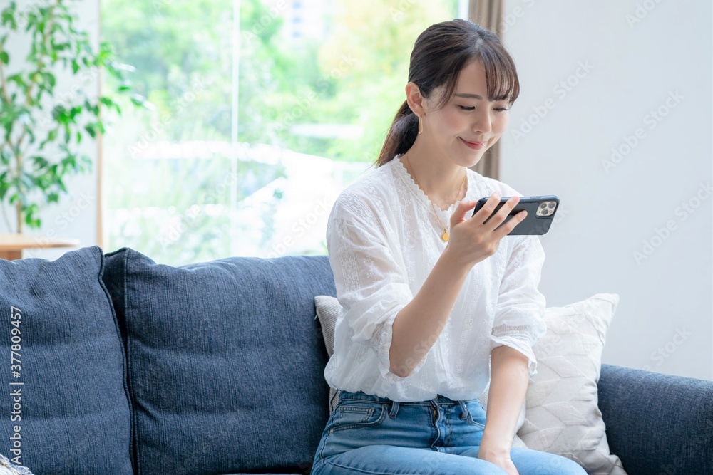 Obraz premium 家で携帯を触るアジア人女性 