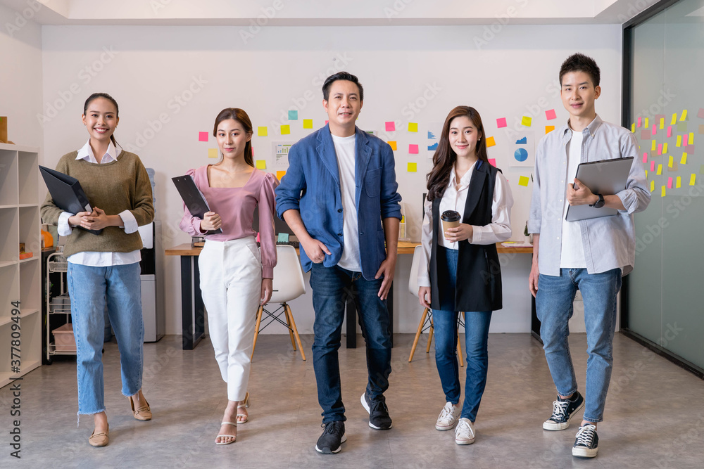 Portrait of young asian businesspeople standing indoors in office, looking at camera.Successful and confident business Startup Diversity team,Corporate of modern colleague