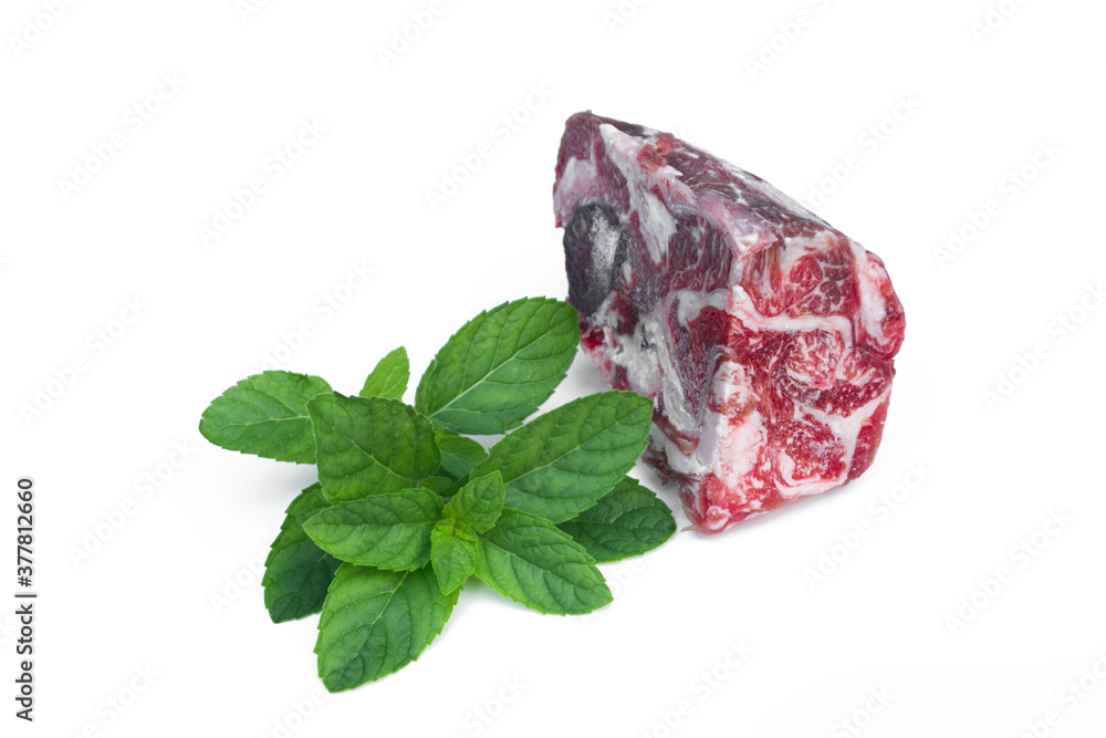 Obraz premium Frozen beef isolated on white background decorated with greens.