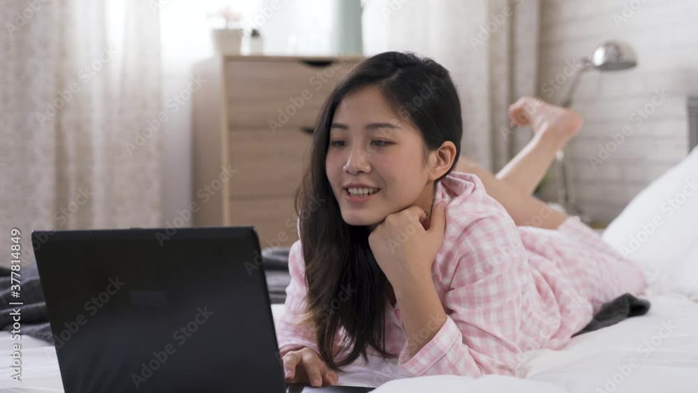 Asian girl lying prone is surfing the net leisurely carefree holiday morning is having fun reading posts on social media with notebook. Asian girl lying prone is surfing the net leisurely carefree holiday morning is having fun reading posts on social media with notebook.