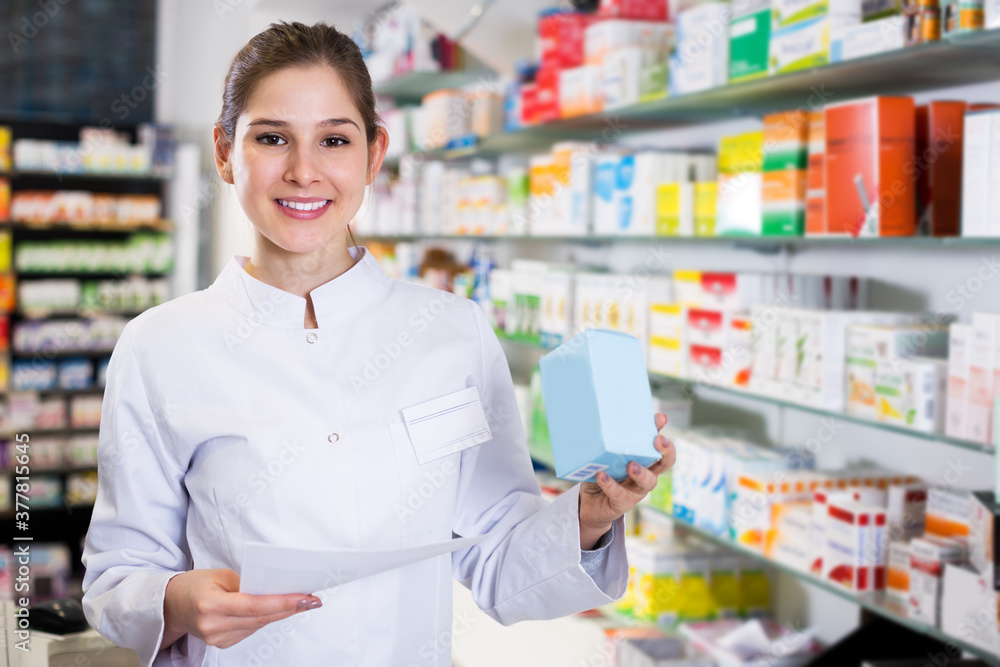 Smiling woman pharmacist is standing with medicines in pharmacy