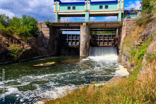 фотографія Flowing water with water spray from the open sluice gates of a small dam