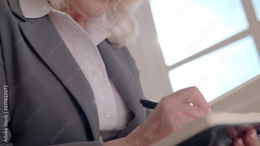 An adult gray-haired woman is working in the office. An adult gray-haired woman is working in the office.