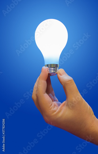 Lighting lamp in hand on blue