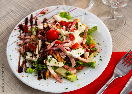 Tourangelle salad with bacon, cherry tomatoes and cheese at plate with balsamic