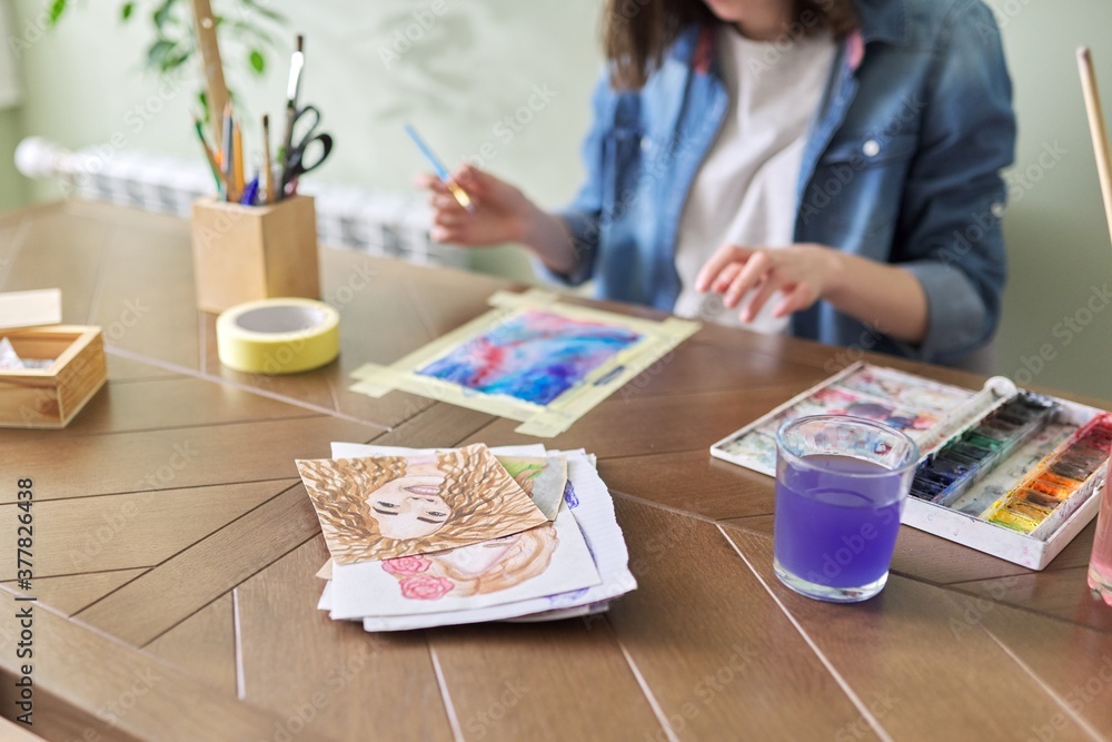 Teenager girl painting with watercolors, sitting at home at the table Teenager girl painting with watercolors, sitting at home at the table