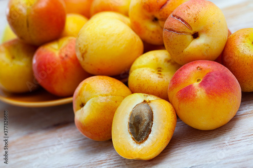 Fresh juicy apricots whole and halves on wooden table. Concept of health benefits of fruits