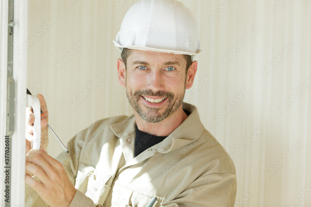 smiling construction worker stood by window smiling construction worker stood by window
