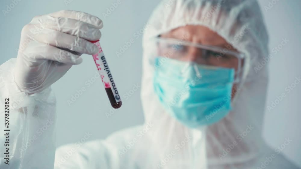 focus pull of scientist in hazmat suit holding test tube isolated on grey focus pull of scientist in hazmat suit holding test tube isolated on grey