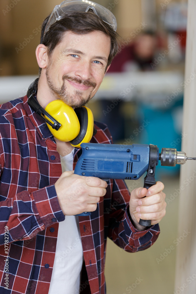 portrait of smiling young man holding power drill portrait of smiling young man holding power drill